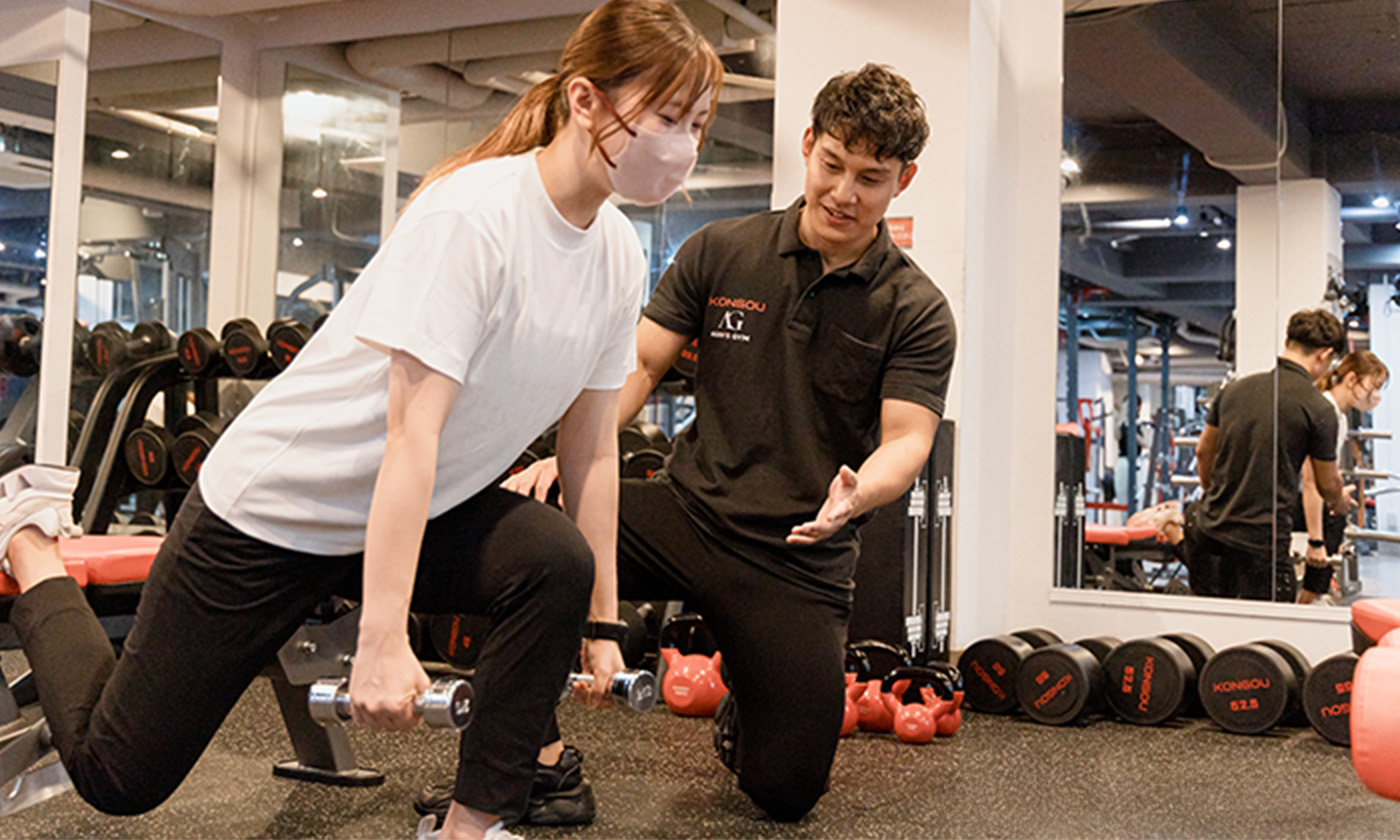 Trainer guiding a beginner through dumbbell training